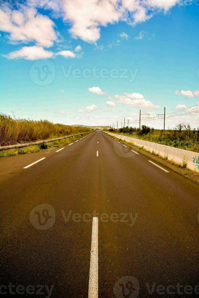 an empty road with a blue sky and clouds photo