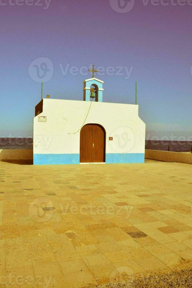 a small white building with a blue door and a cross on top photo