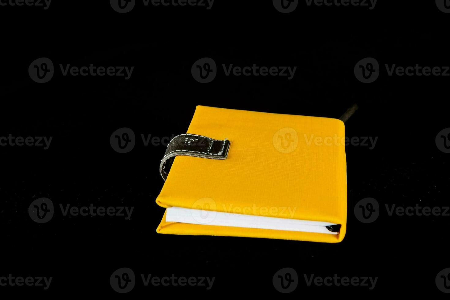 un amarillo cuaderno con un negro cubrir en un negro antecedentes foto