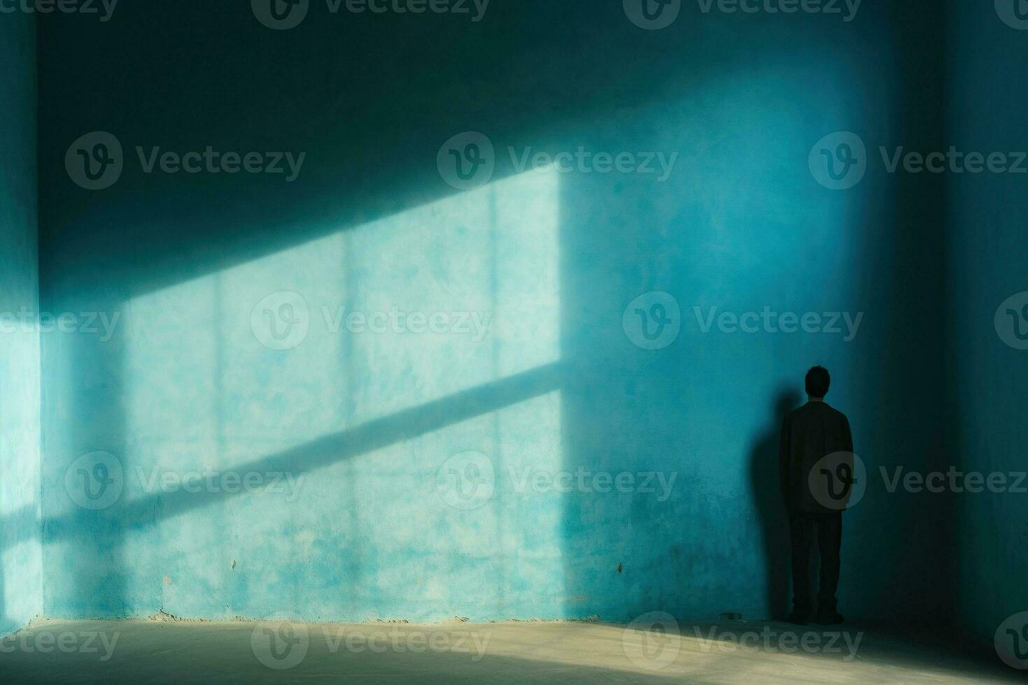A lonely man stands facing the wall in an empty room. Blue wall with shadows. Concept of human loneliness, social problems. Generative AI photo