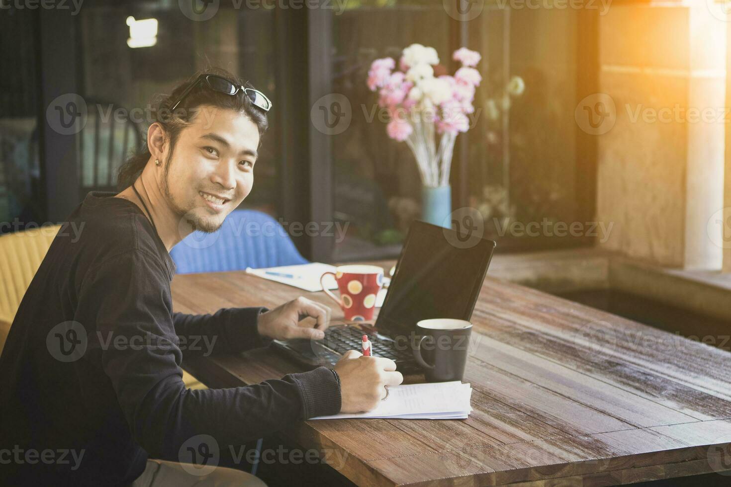 asian freelance man write on paper with computer laptop on working table photo
