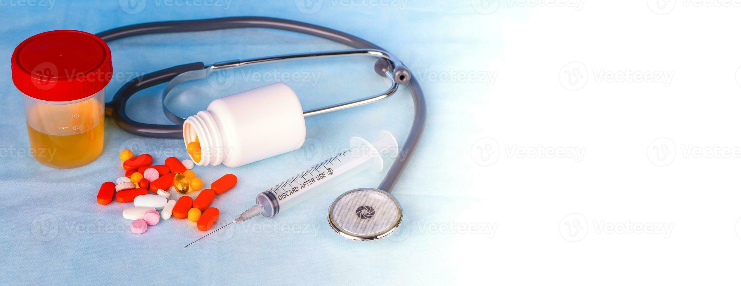 Close up of urine containers for test, syringe, phonedoscope and colored pills on blue background photo