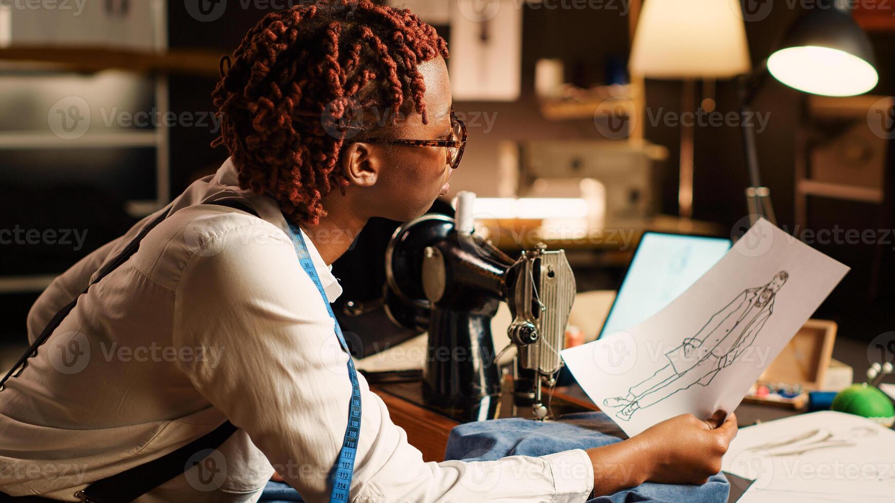Designer using sewing machine to design custom made clothes, craftsmanship concept. Female couturier working on fashion collection in tailor workshop, handmade items clothing at table. photo