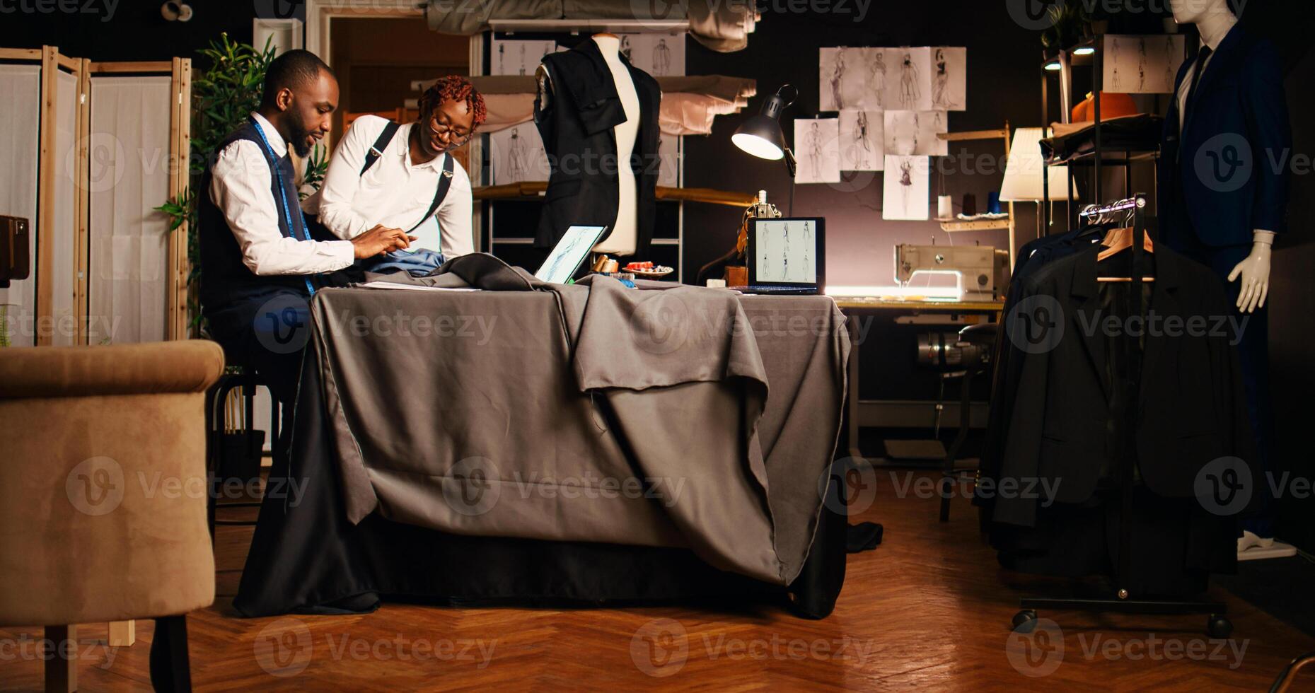 Couturiers preparing fabric garment for fashion line sewing process, picking perfect model on outlines. Tailor and assistant working on clothing design creation. Handheld shot. photo