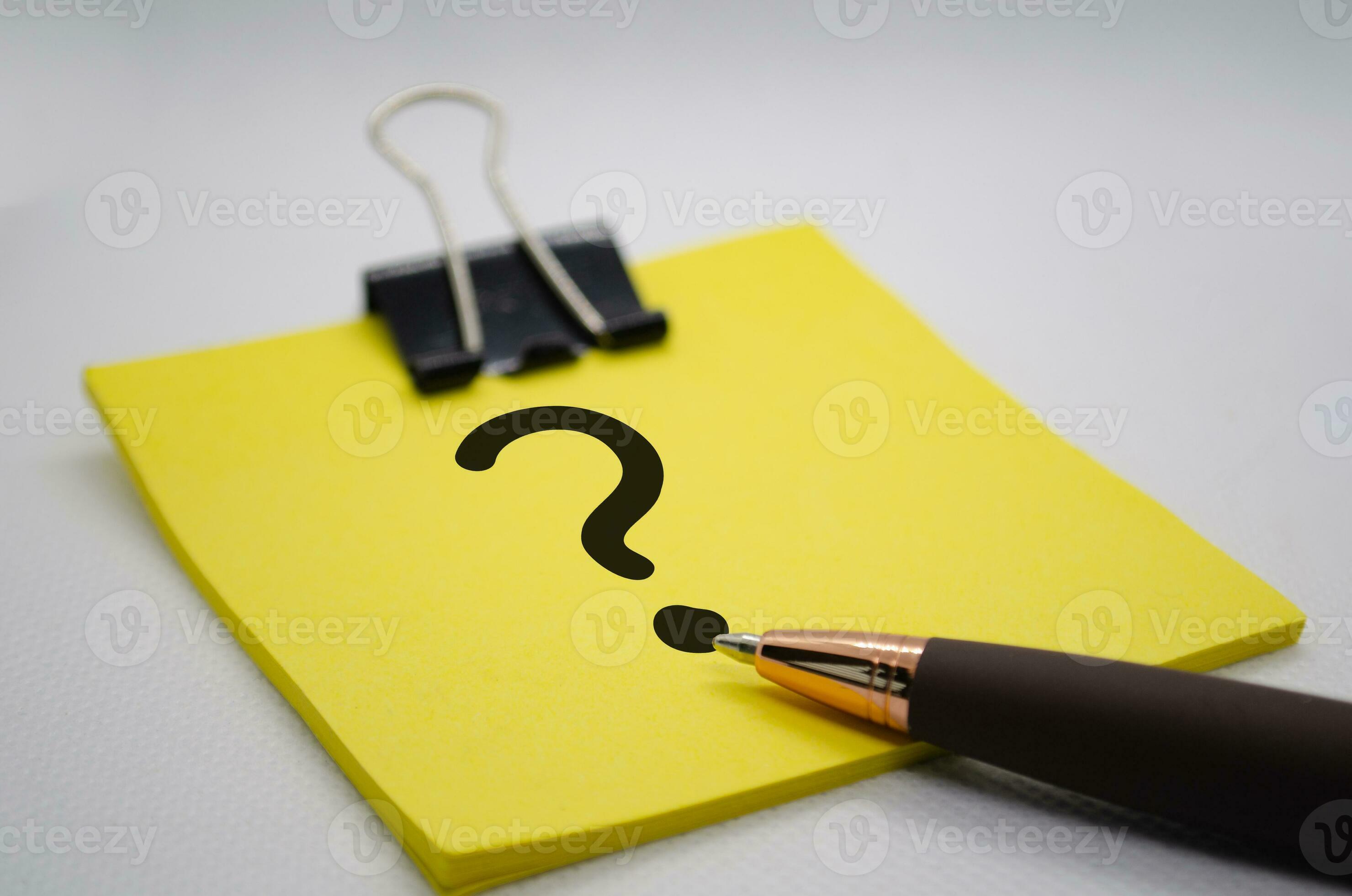 Close up of question mark on notepad with pen on white background