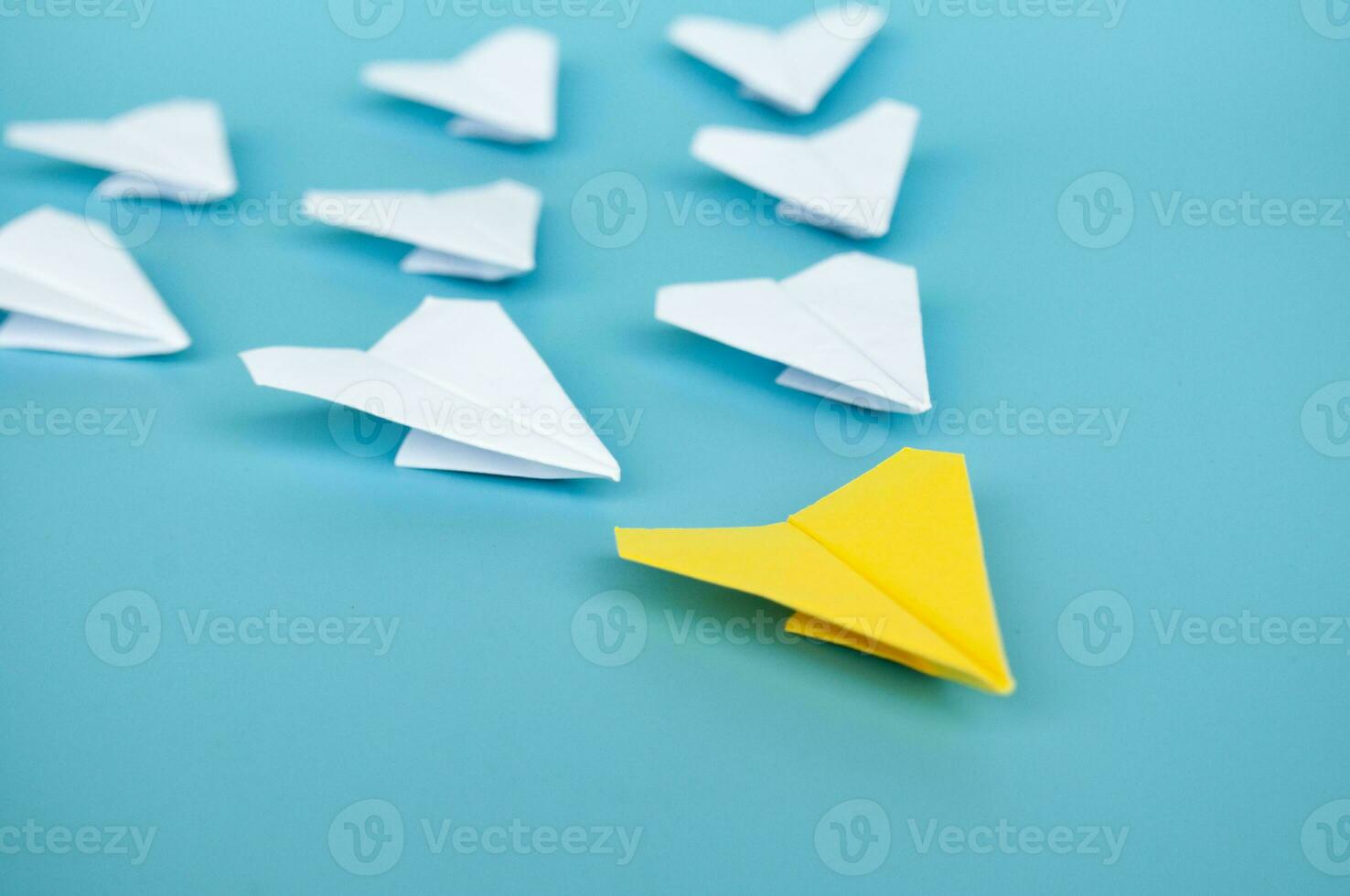 Top view of yellow paper airplane origami leading other white paper airplanes photo