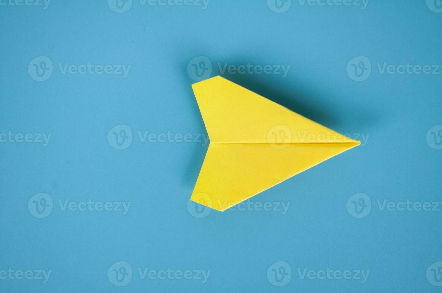 Top view of yellow paper airplane on blue background. Space for text or ideas. photo