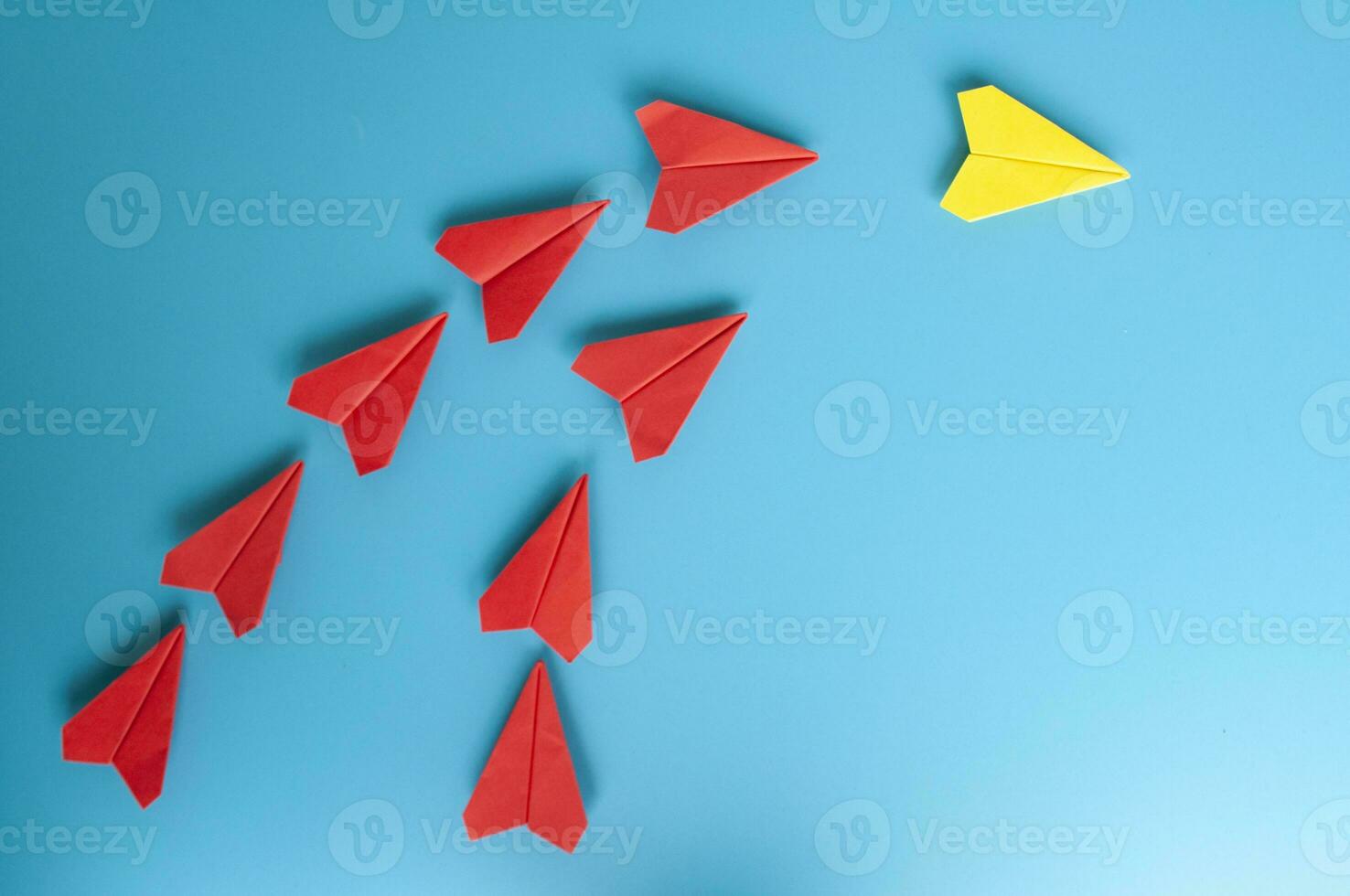 Top view of yellow paper airplane origami leading red paper airplanes. With copy space for text photo