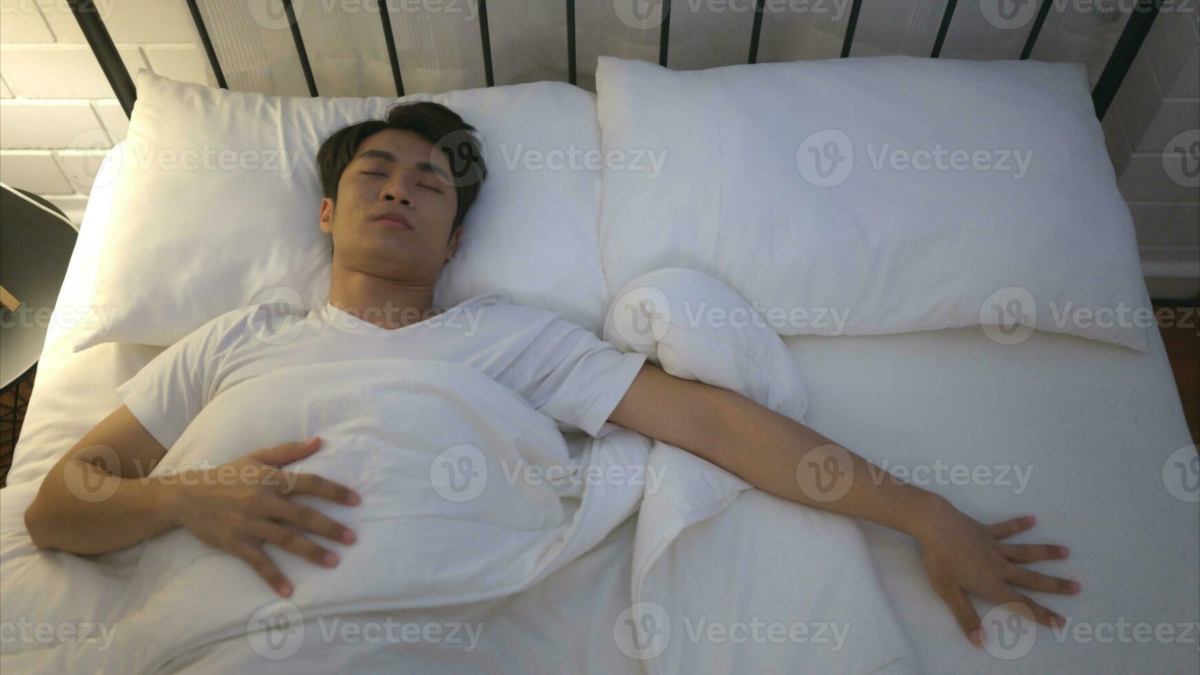 Young Asian man lying on the bed Use his hand to fumble his wife who thinks her woke up together that morning. photo