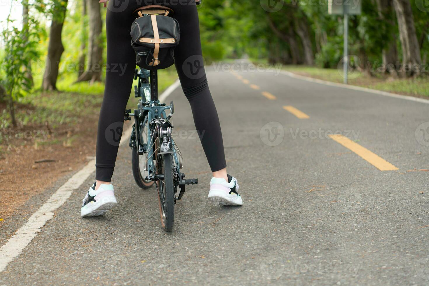 joven mujer ciclista montando bicicleta en la carretera en parque. sano estilo de vida concepto foto