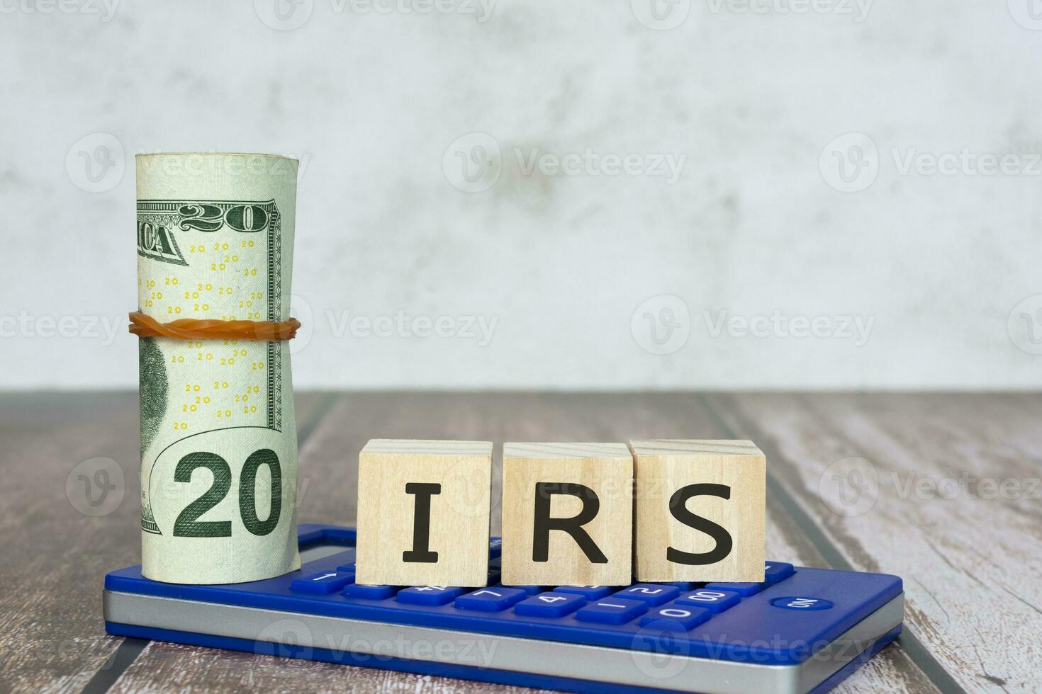 IRS Text IRS on wooden blocks with dollar bill and calculator on wooden table. photo