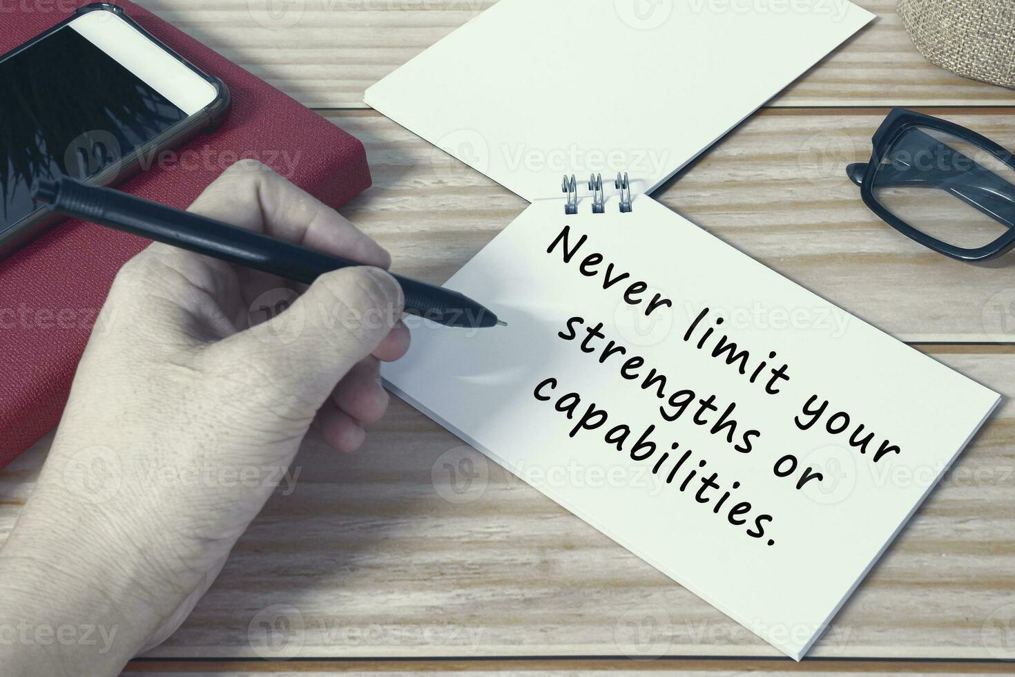 Motivational quote on notepad. Never limit your strengths or capabilities. photo