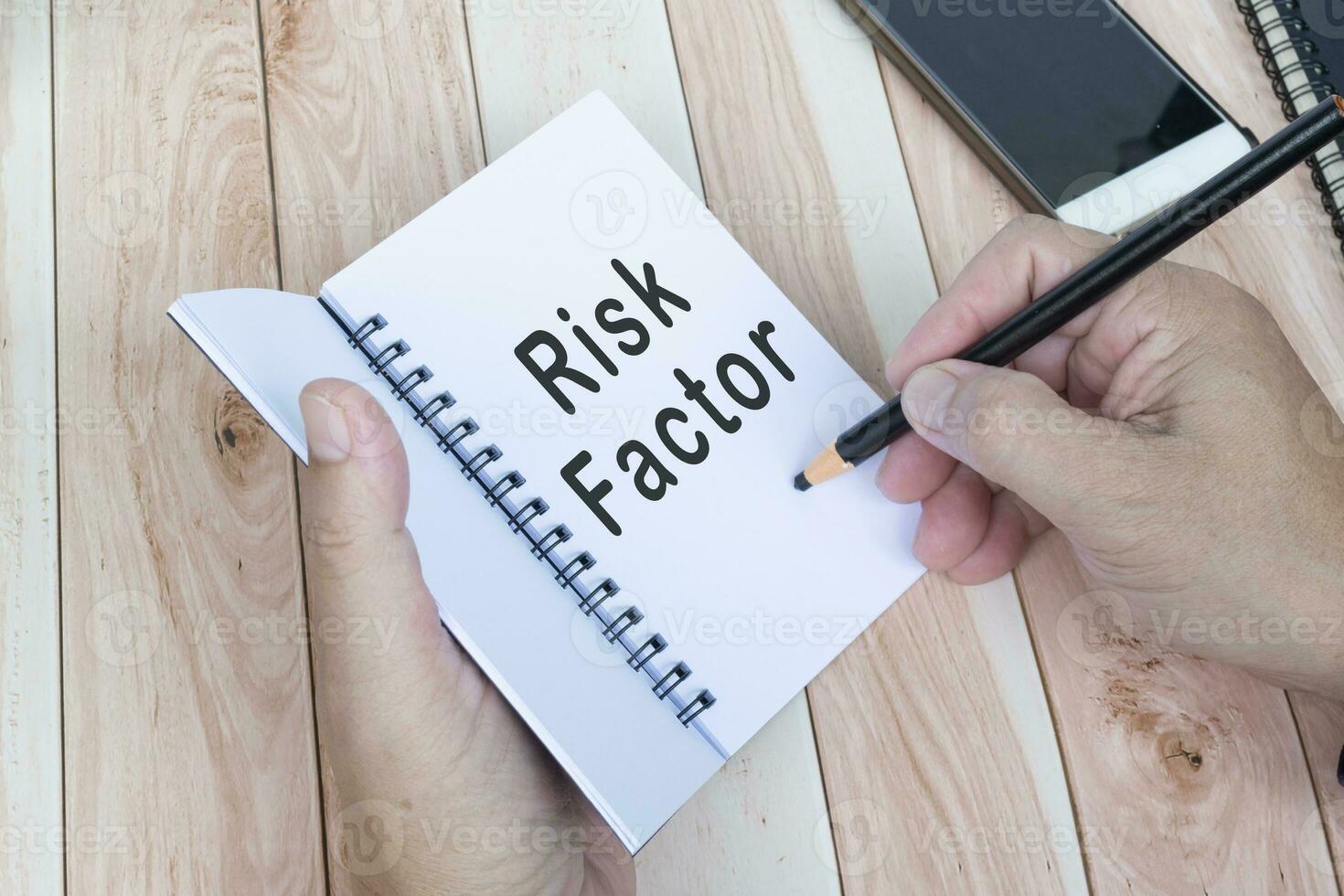 Businessman hands with pen writing notebook on office desk. Risk Factor. photo