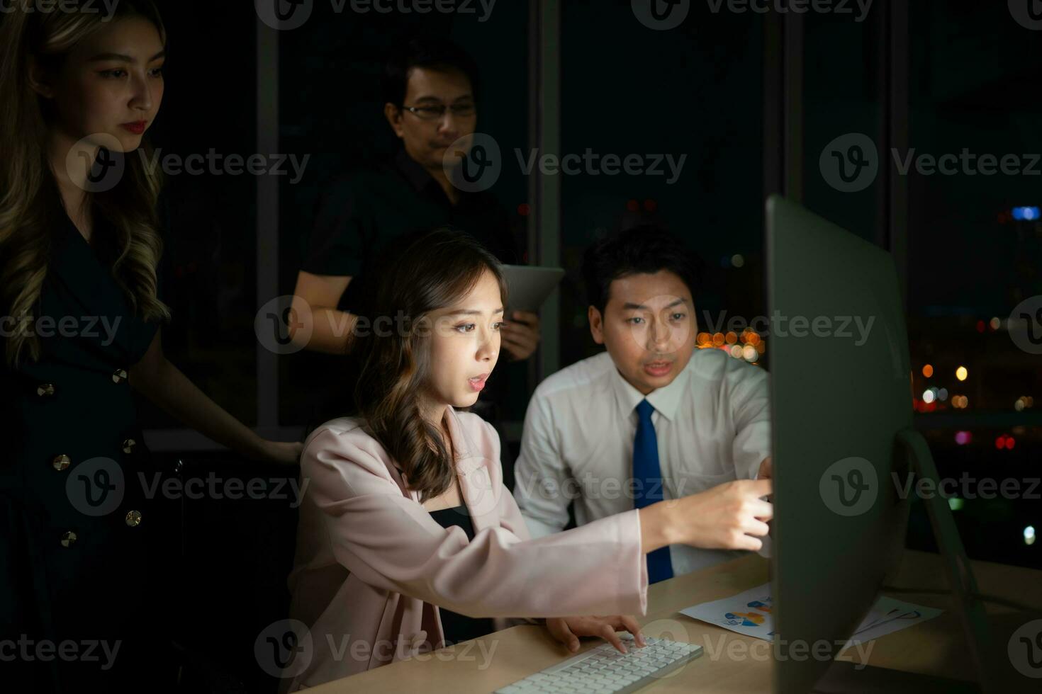 Group of business people working in office at night. Business concept. photo