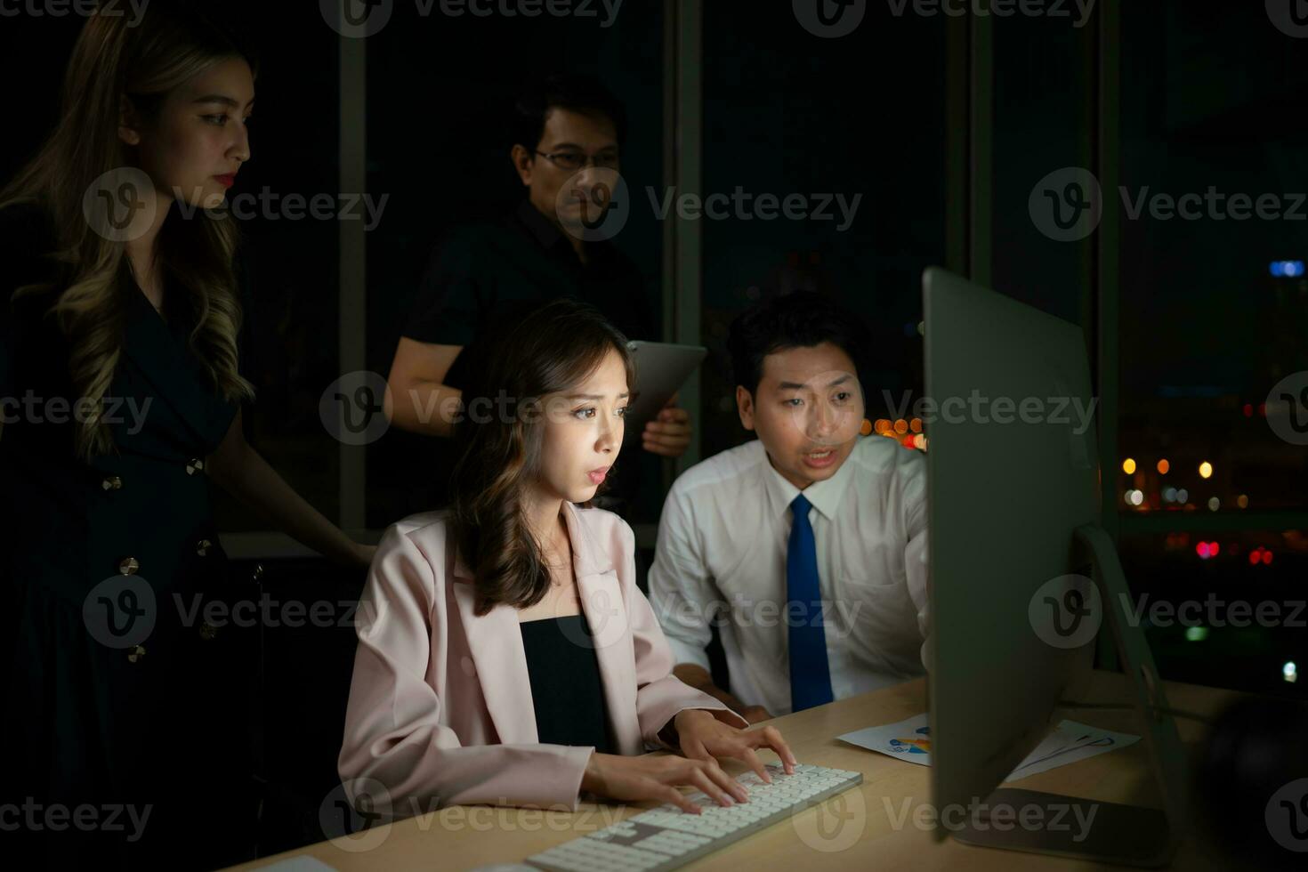 Group of business people working in office at night. Business concept. photo