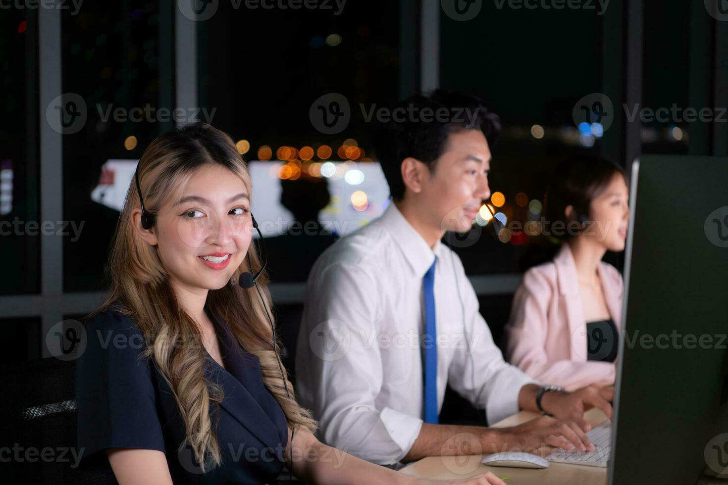 Group of broker international stock traders wearing headset working actively at night in office, Concept of customer support agent provide service on telephone. photo