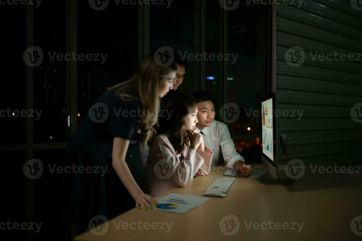 Group of business people working in office at night. Business concept. photo