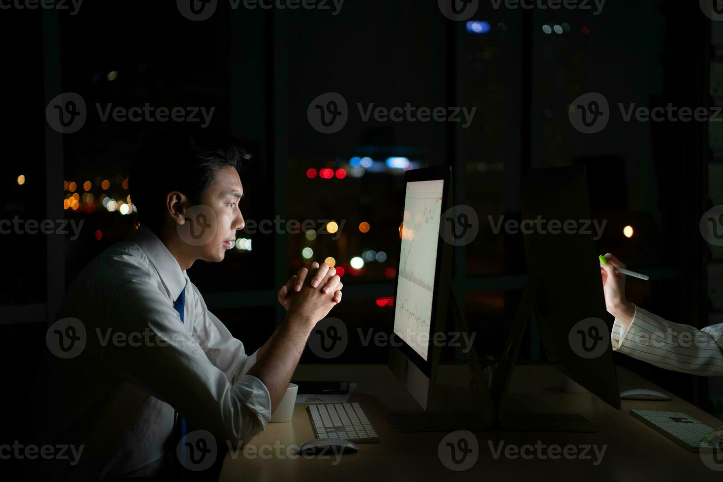 Young Asian broker international stock traders working at night in office using computer and thinking. photo