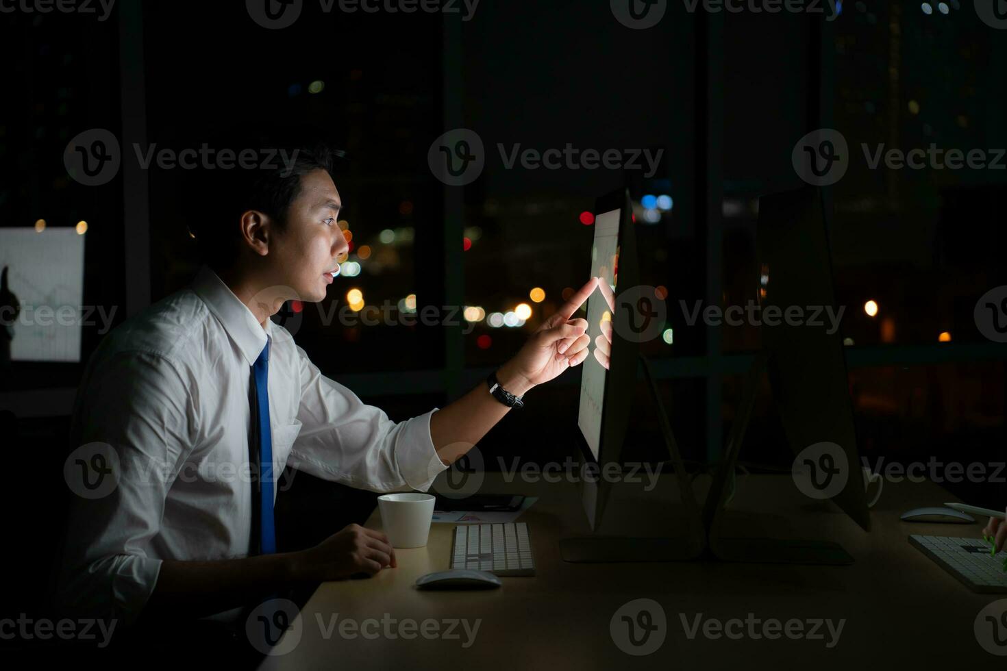 Young Asian broker international stock traders working at night in office using computer and thinking. photo