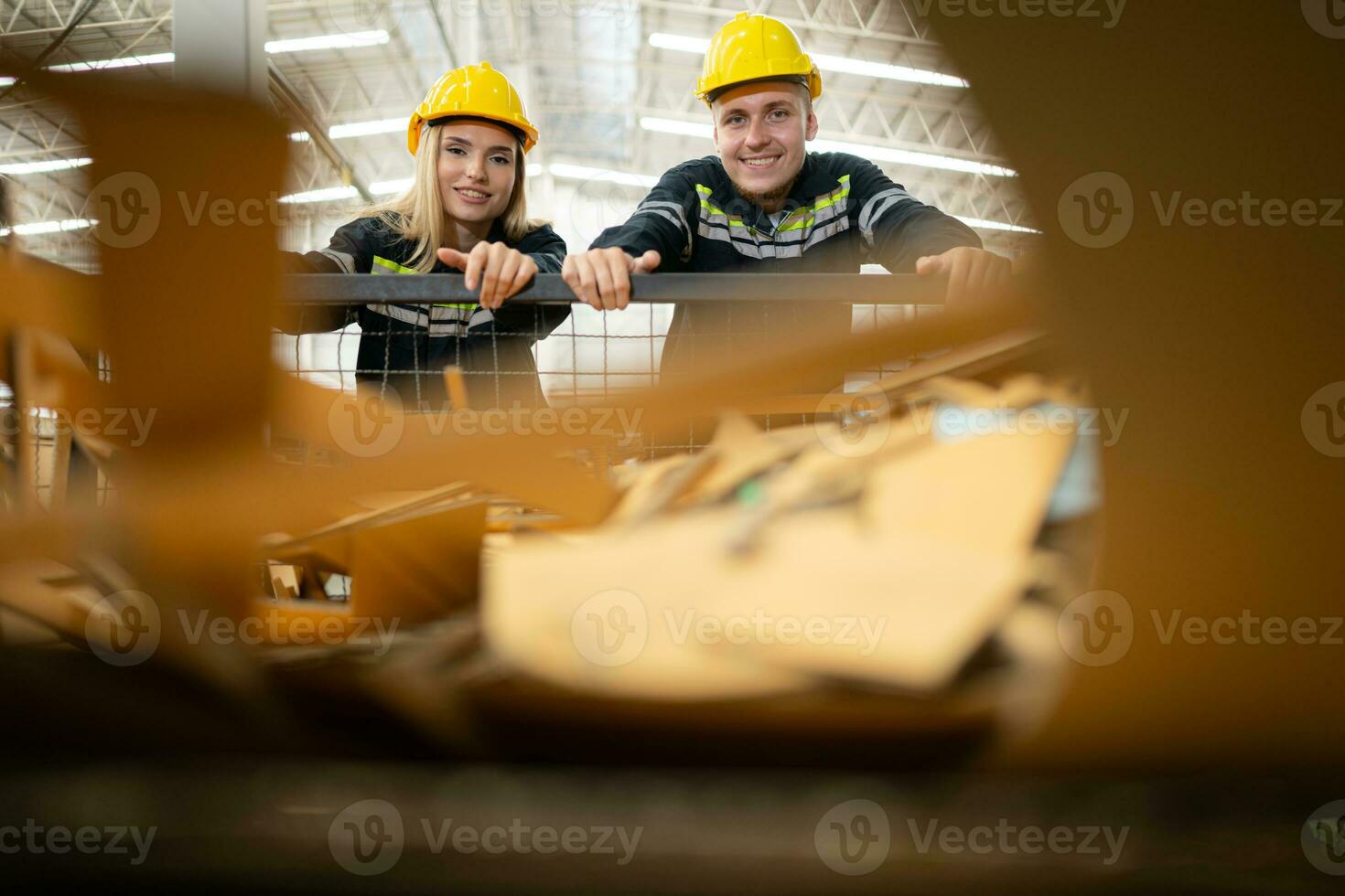 Two factory workers work in a warehouse, pushing a paper cart to be recycled photo