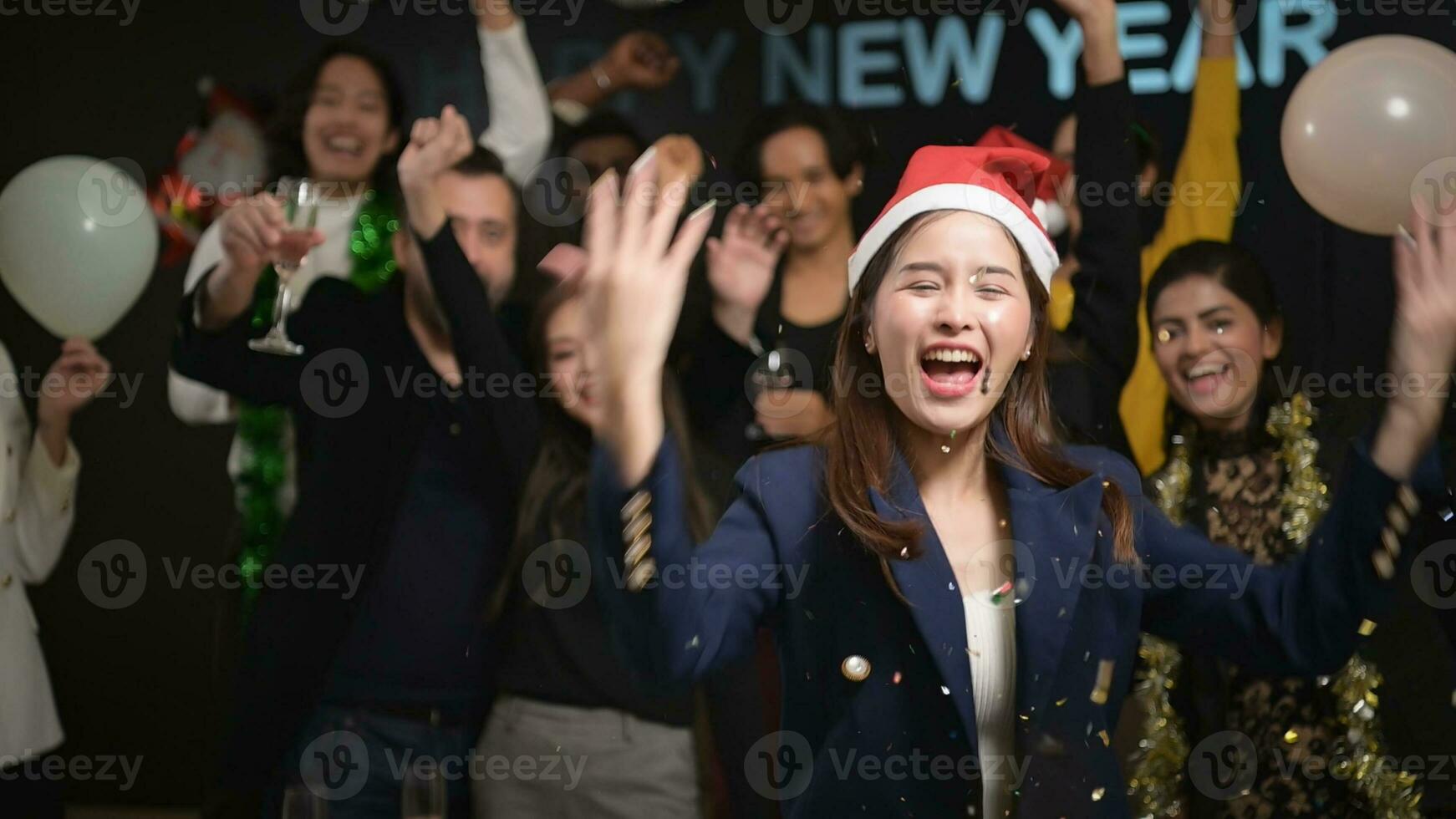 nuevo año fiesta, grupo de joven personas en Papa Noel sombreros soplo papel picado mientras celebrando nuevo año foto