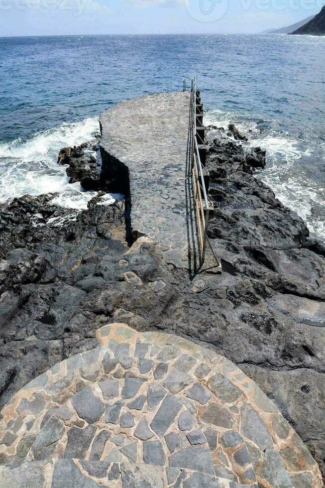 a stone walkway leads to the ocean photo