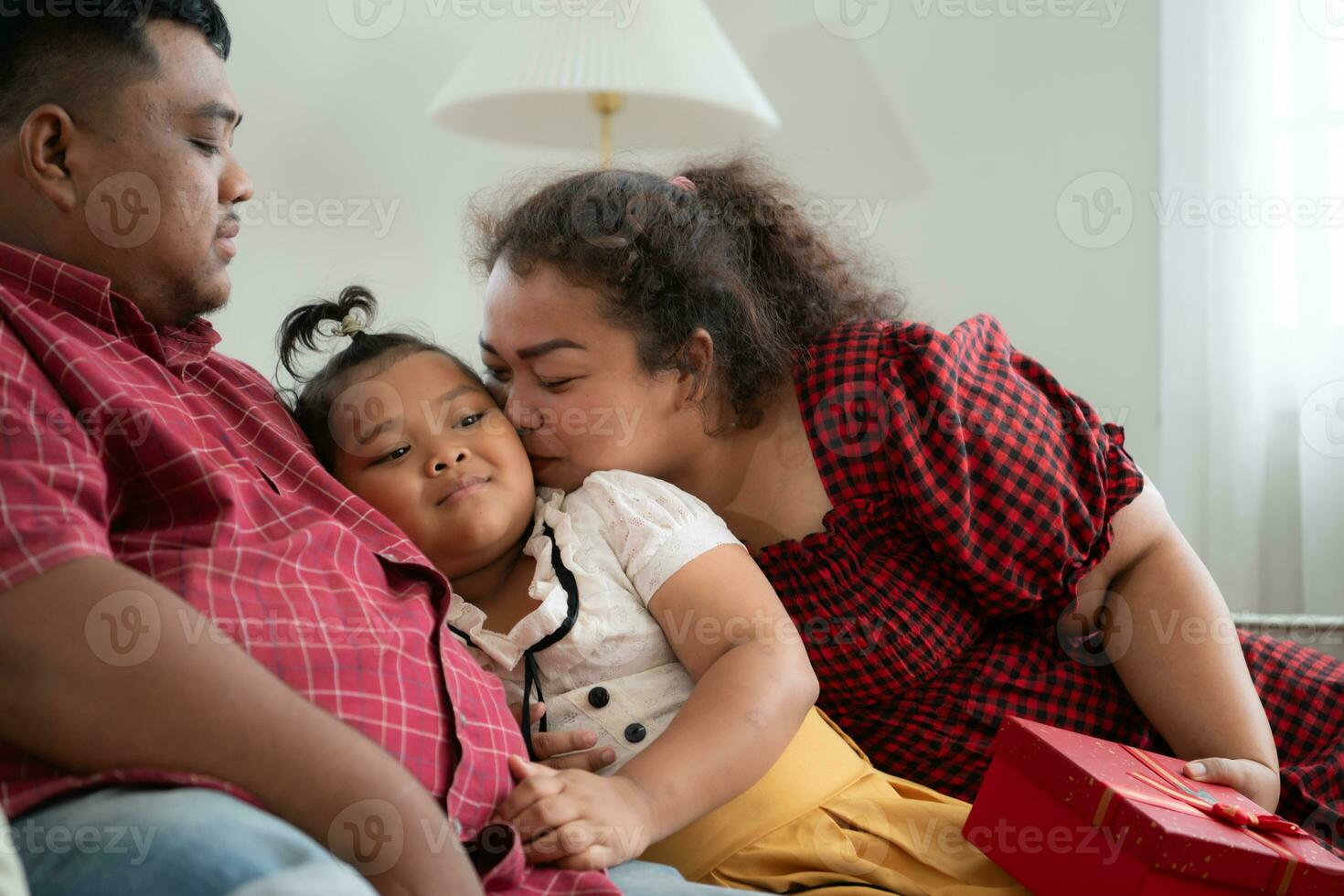 A plus size family with a father wearing a prosthetic leg, Give a gift to a daughter who does well in school and receives acclaim from her teachers, in the living room of the house. photo