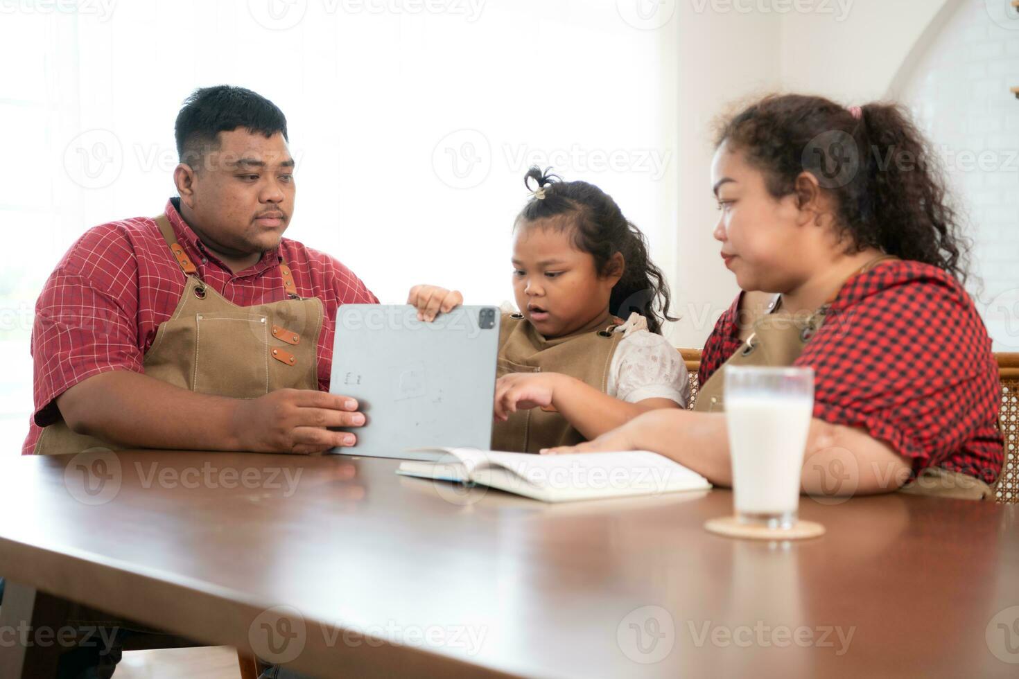 un talla extra familia con un padre vistiendo un protésico pierna, es felizmente ayudando un niño con su deberes y teniendo divertido juntos en el comida habitación de el casa antes de Cocinando juntos foto