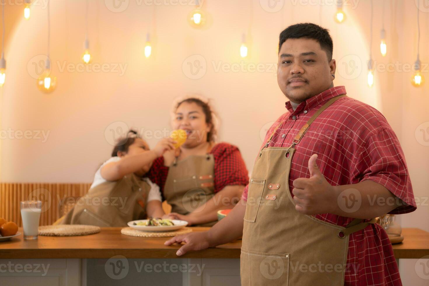 un talla extra familia con un padre vistiendo un protésico pierna, comer juntos después Cocinando y hija bebidas Leche para salud en el comida habitación de el casa foto