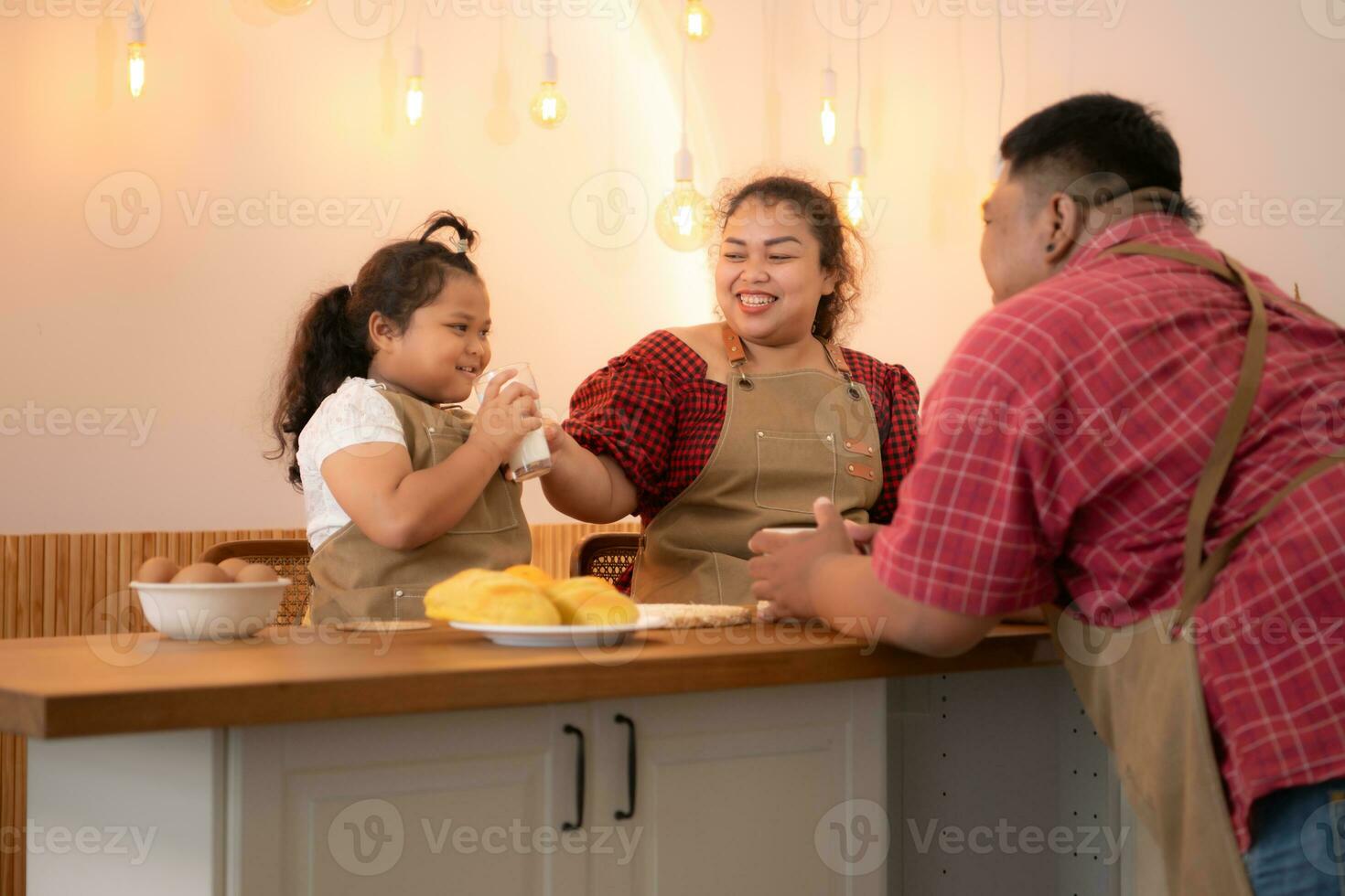 un talla extra familia con un padre vistiendo un protésico pierna, comer juntos después Cocinando y hija bebidas Leche para salud en el comida habitación de el casa foto