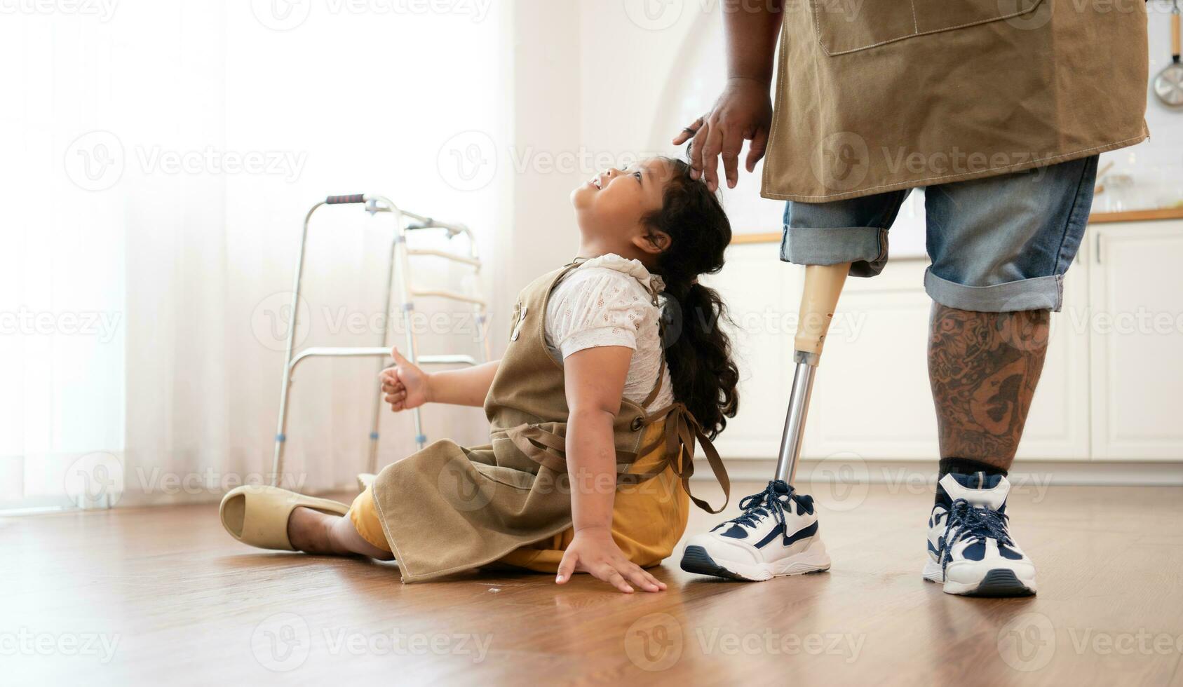 A plus size family with a father wearing a prosthetic leg, The daughter had fun playing with her father before helping cook. in the kitchen room of the house. photo