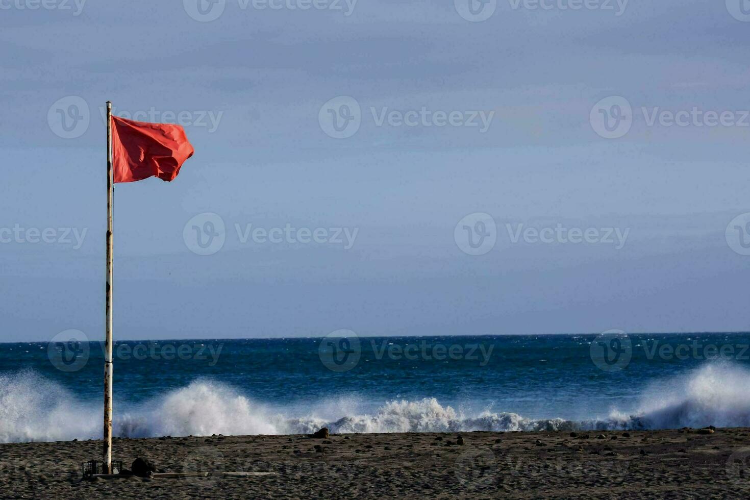 a red flag on the beach near the ocean photo