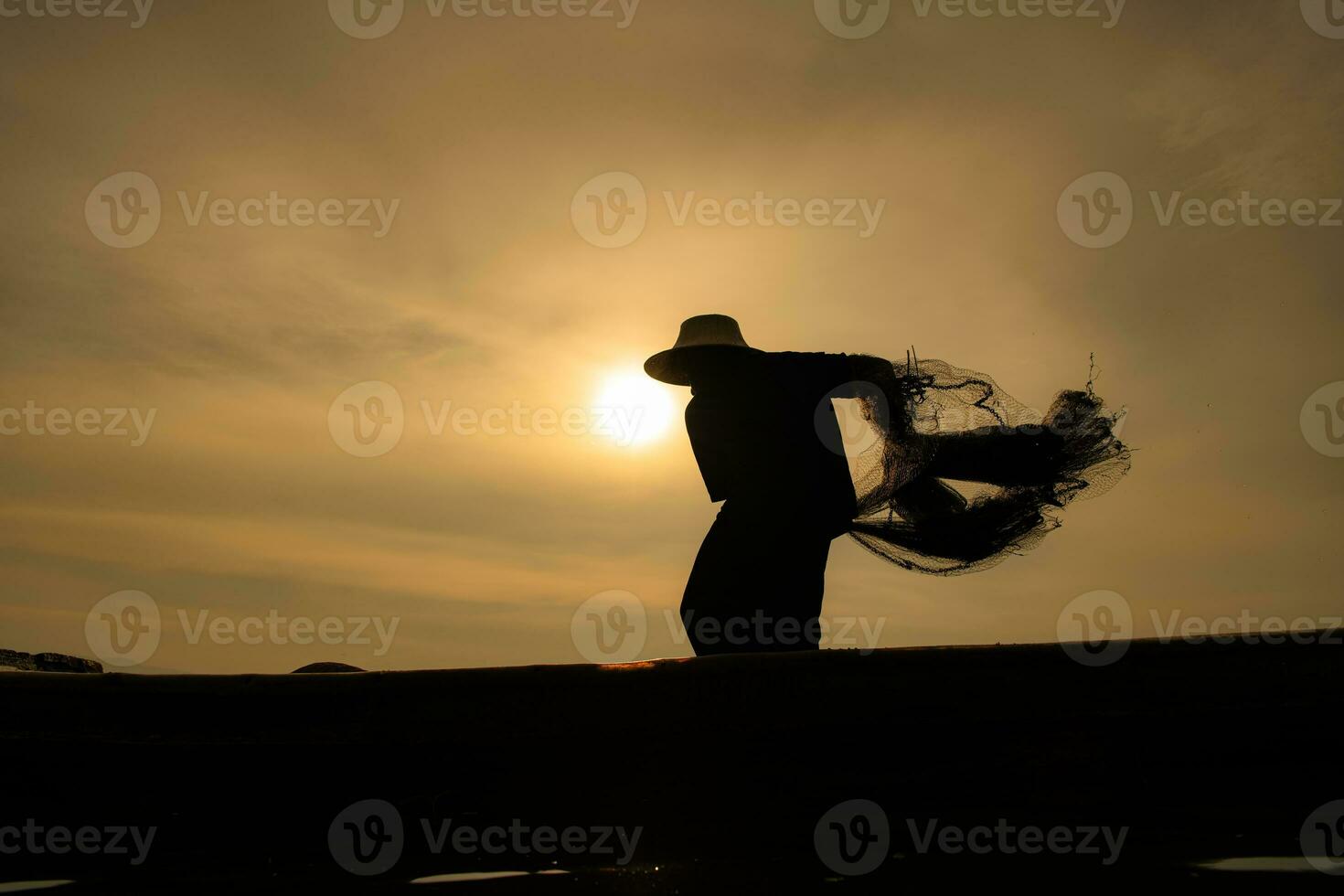 Silhouette of fisherman at sunrise, Standing aboard a rowing boat and casting a net to catch fish for food photo