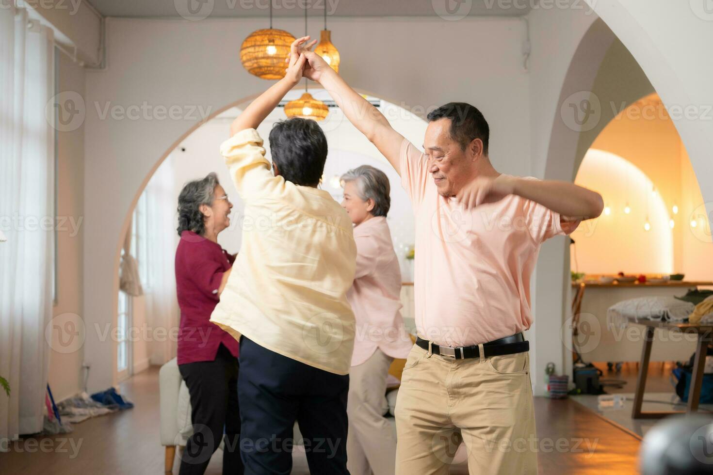 A group of elderly Asian people dance together happily, in the retirement home photo