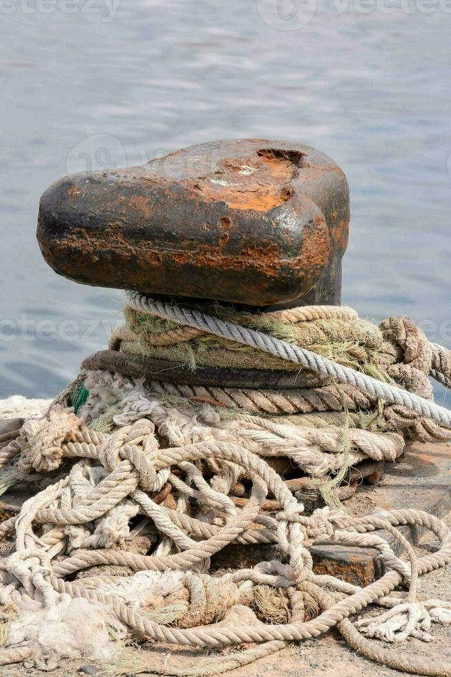 a rusted anchor on a dock with rope photo