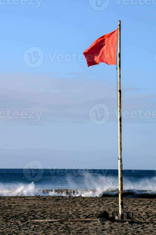 a red flag on the beach near the ocean photo