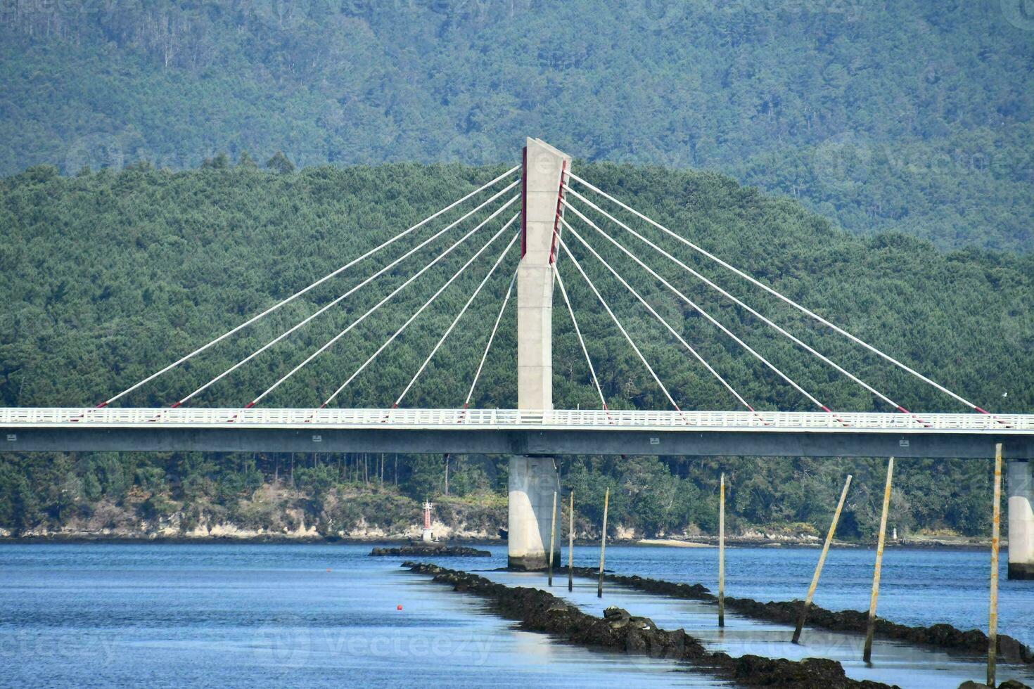 a bridge spanning over the water with mountains in the background photo