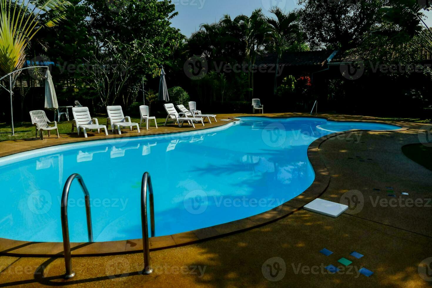 a swimming pool in a backyard with lawn chairs and umbrellas photo