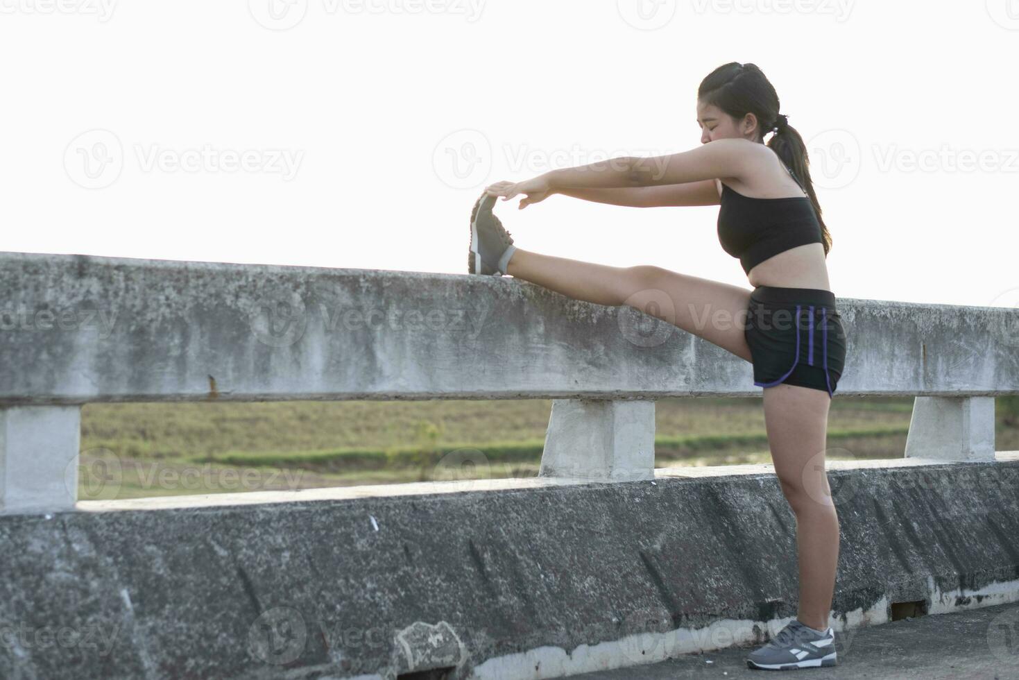 Asian woman warming up and stretching before running on a bridge in the morning in the sun,motion blur,concepts of running for good health. photo