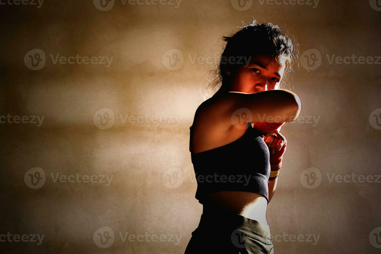 Young woman practicing boxing at the gym, she wears boxing gloves. photo