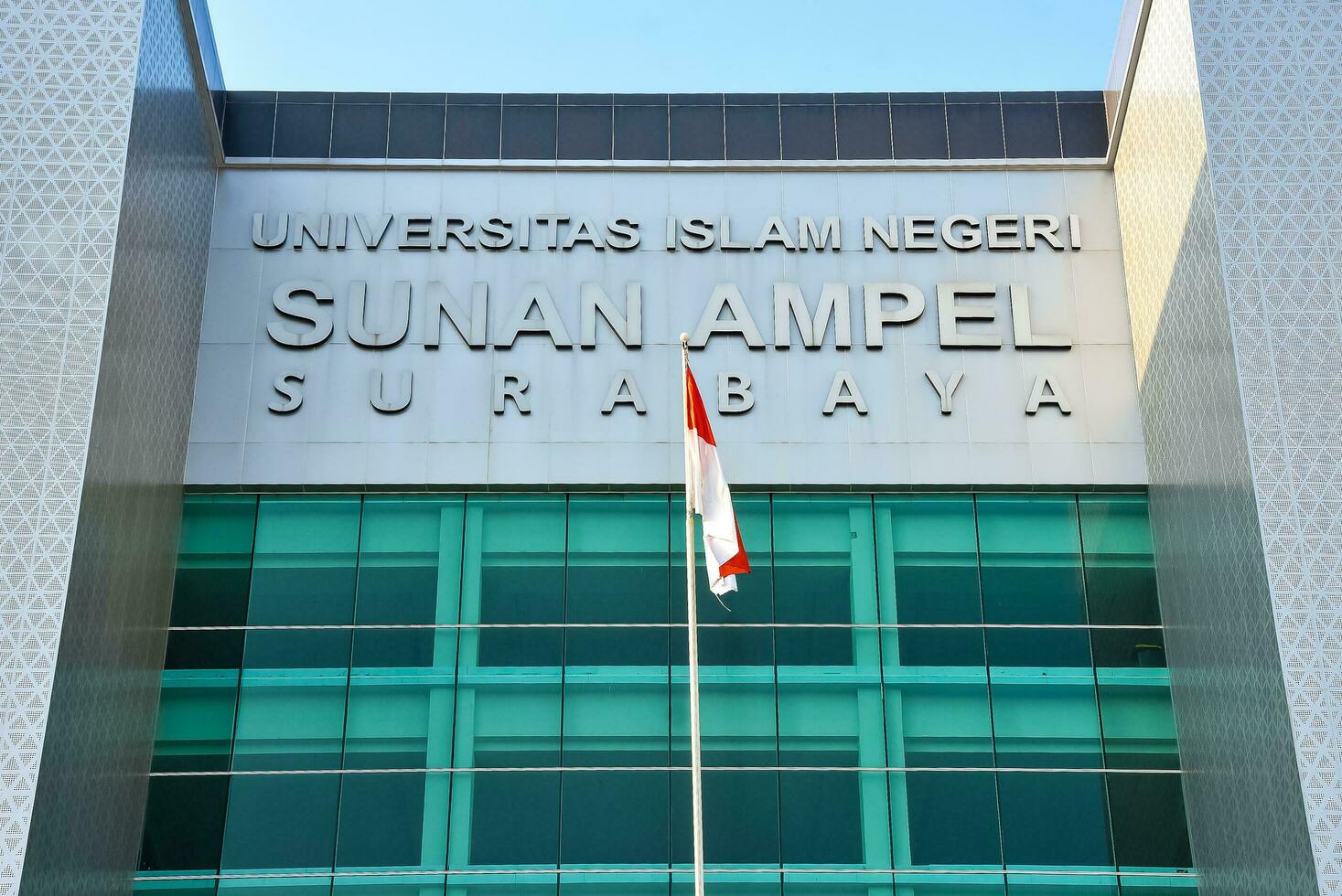 Surabaya, Indonesia.  08 15 2023. Indonesian red and white flag flying in front of one of the main buildings of Sunan Ampel State Islamic University UIN, lecture. photo