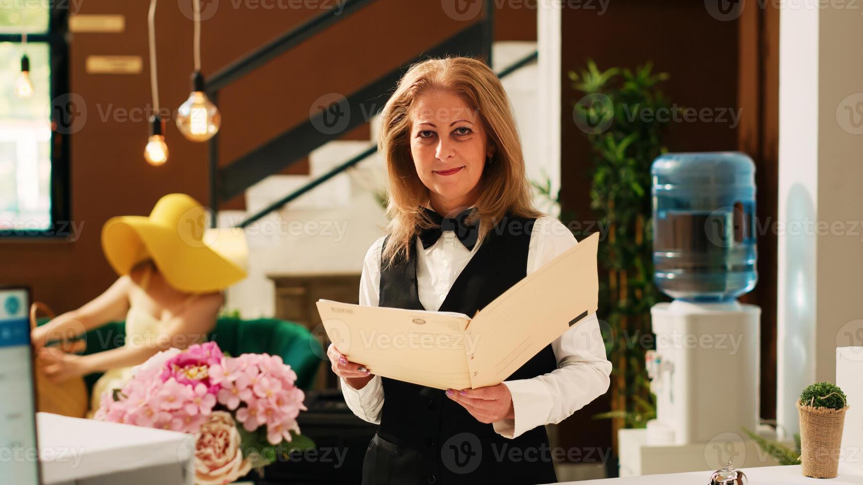 Hotel concierge reviewing bookings or reservations, working at reception in lobby to help travellers with check in procedure. Receptionist in front desk, tropical exotic resort. photo