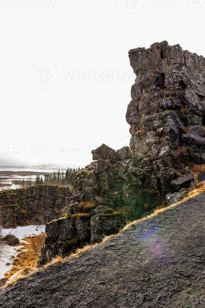 Natural volcanic rocky cliffs form mountain wall in icelandic national park, majestic highland hills made of concrete stone. Beautiful Iceland wilderness in nordic thingvellir valley. photo