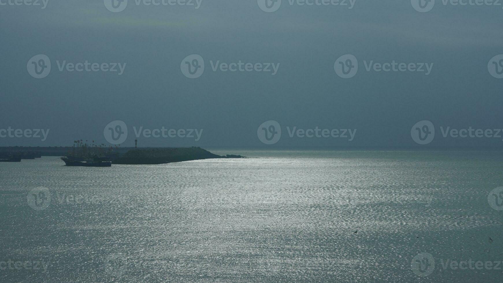 The peaceful sea view with the fishing boat sailing on it in the cloudy day photo