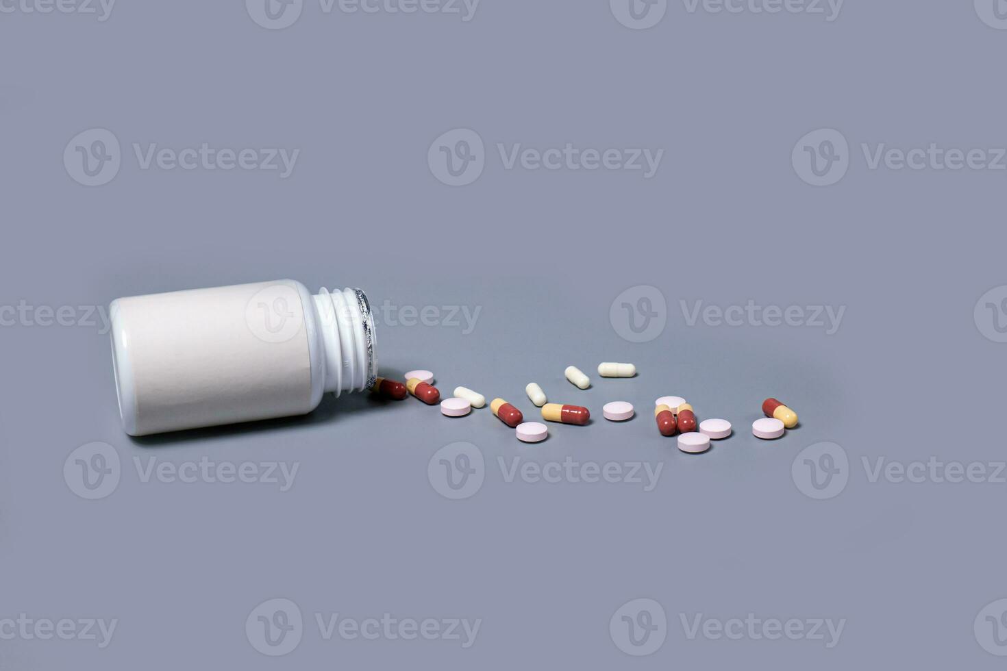 Pills spilling out of pill bottle white and two-colored capsules pills  Medicines and prescription pills flat lay background. White medical pills and tablets spilling out of a drug bottle. photo