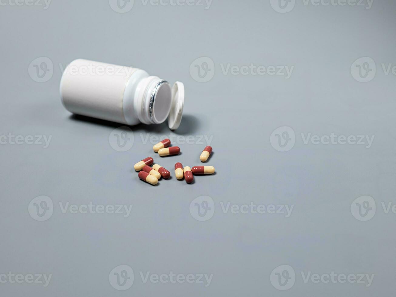 Pills spilling out of pill bottle  two-colored capsules pills  Medicines and prescription pills flat lay background. White medical pills and tablets spilling out of a drug bottle.Copy space for text photo