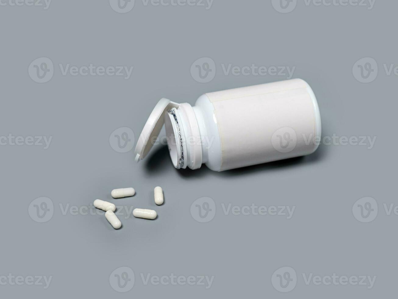 Pills spilling out of pill bottle white  capsules pills  Medicines and prescription pills flat lay background. White medical pills and tablets spilling out of a drug bottle.Copy space for text photo