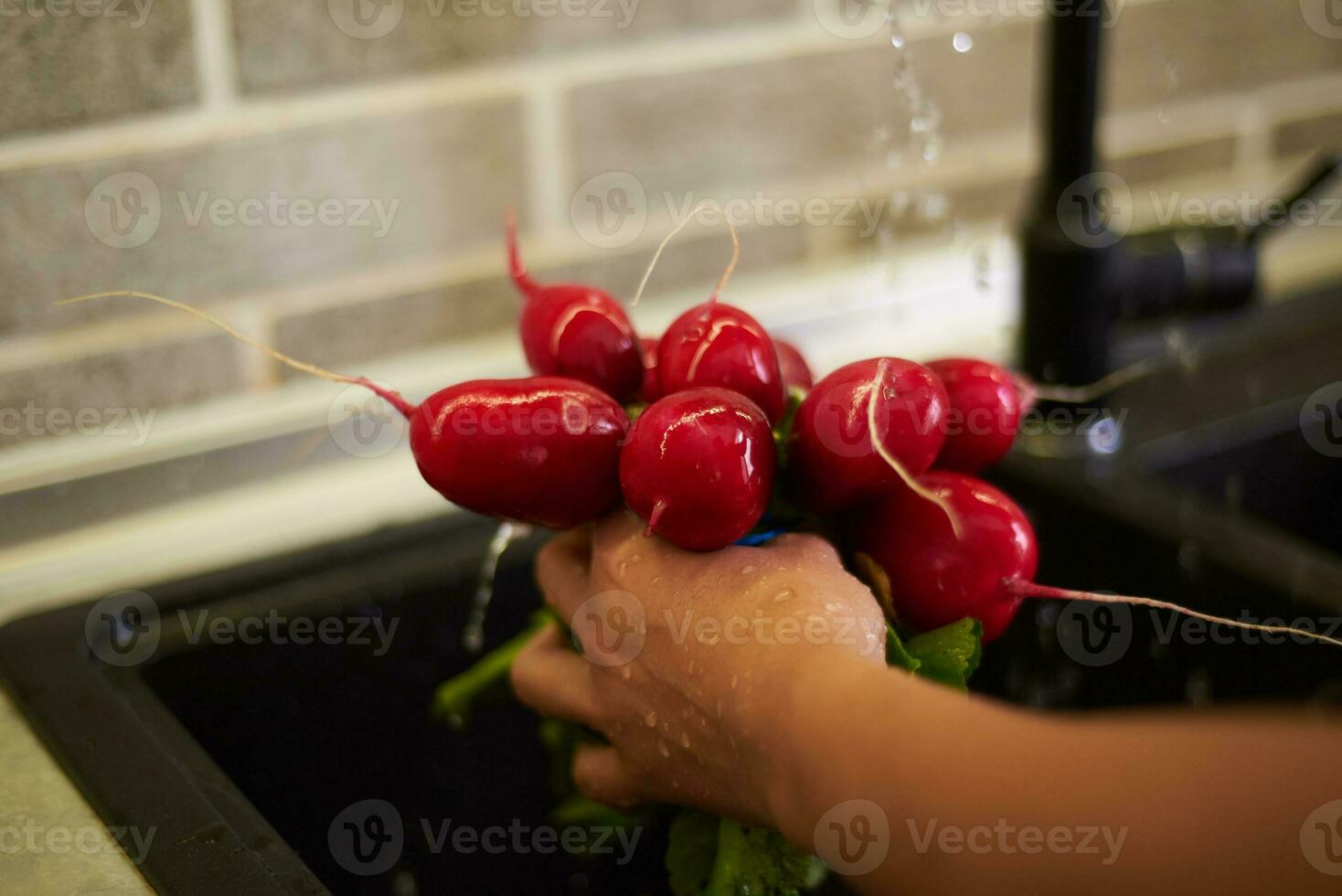 detalles en el manos de un mujer ama de casa Lavado Fresco orgánico rábano hojas en cocina hundir, debajo fluido agua foto