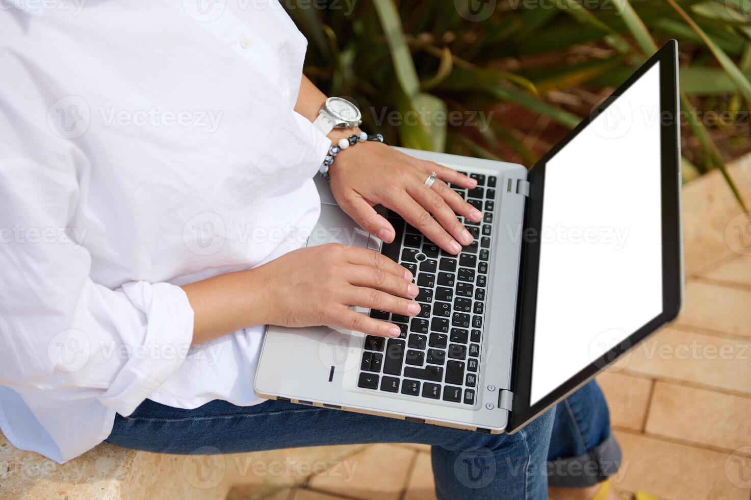 View from above of female manager hands typing text on laptop keyboard. White blank mockup screen with copy ad space photo