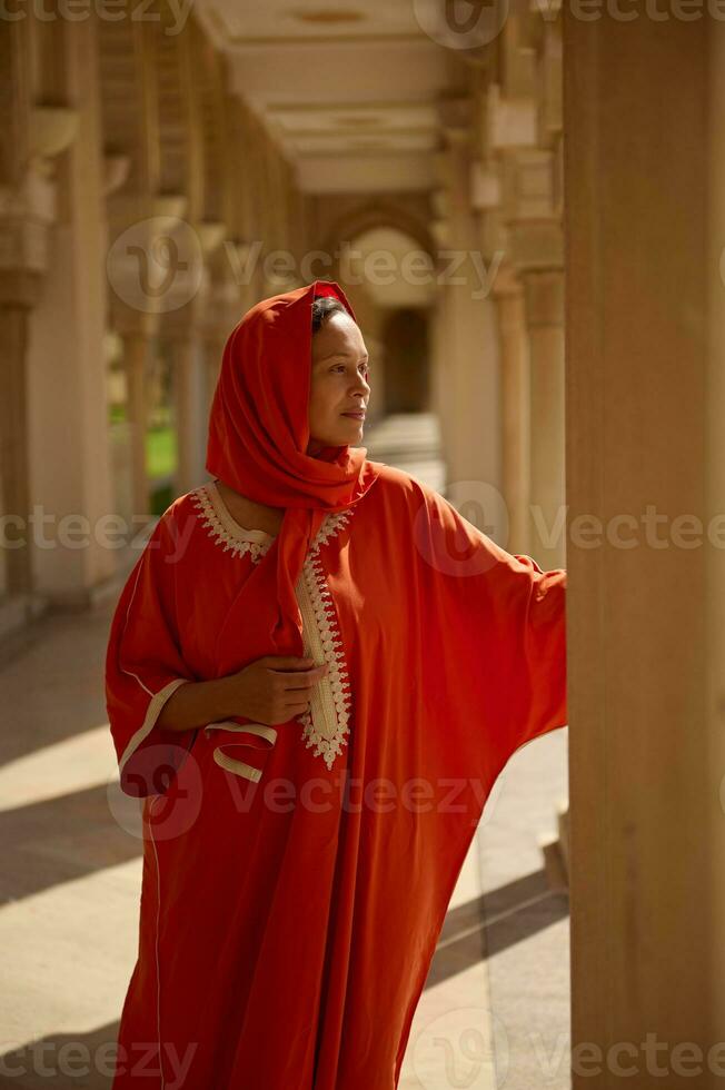 Middle Eastern Muslim woman walking along the mosque Hassan II marble columns. Islamic fashion and Arabian style photo